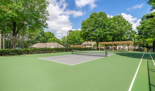 a tennis court with trees and a building in the background